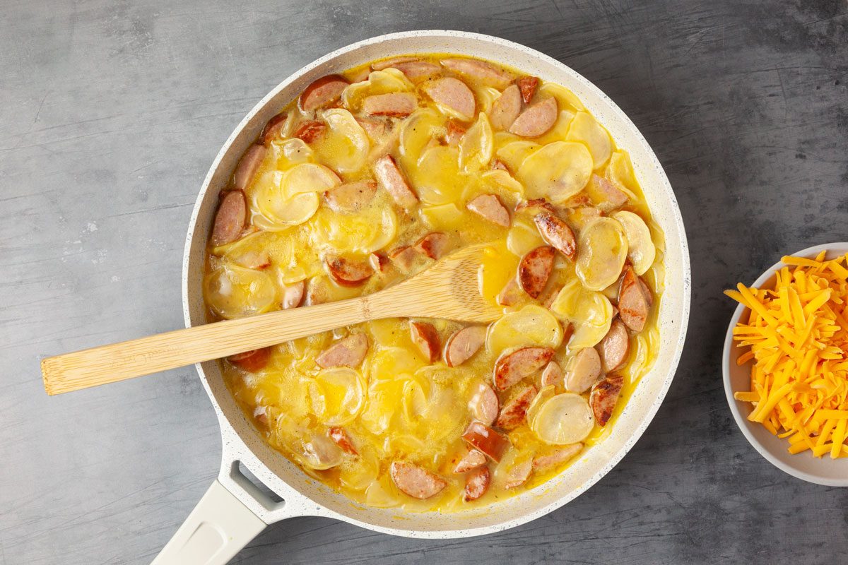 Step 1 of Taste of Home Scalloped Potatoes and Sausage is to brown the sausage and cook the potatoes