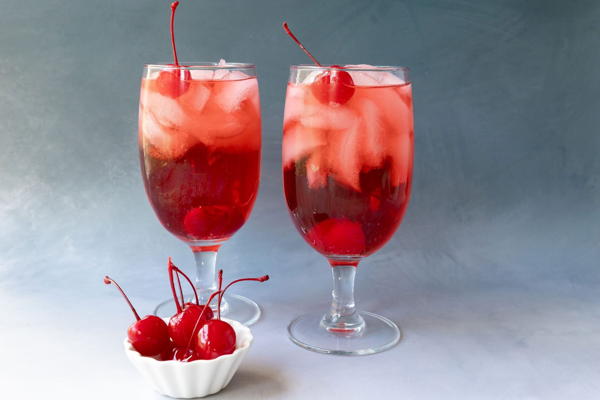 Garnish the Shirley Temple drink with a stemmed maraschino cherry and serve