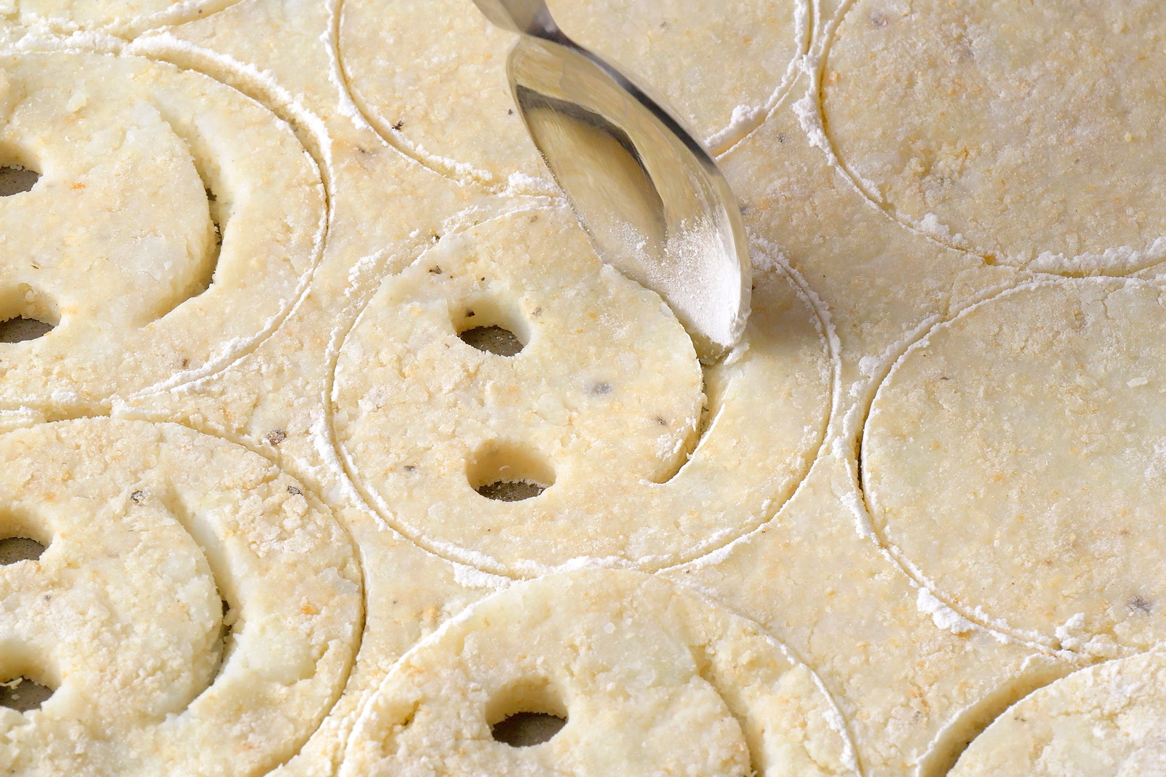 Using a spoon to make happy mouth in the potato dough circles
