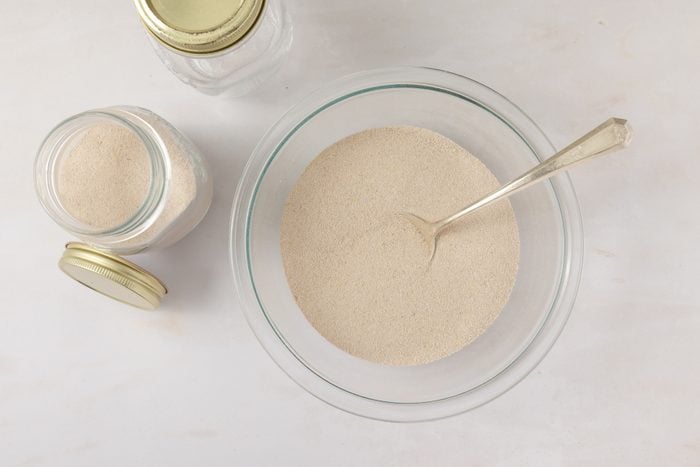 Spiced tea ingredients being combined in mixing bowl and stored in air tight containers.
