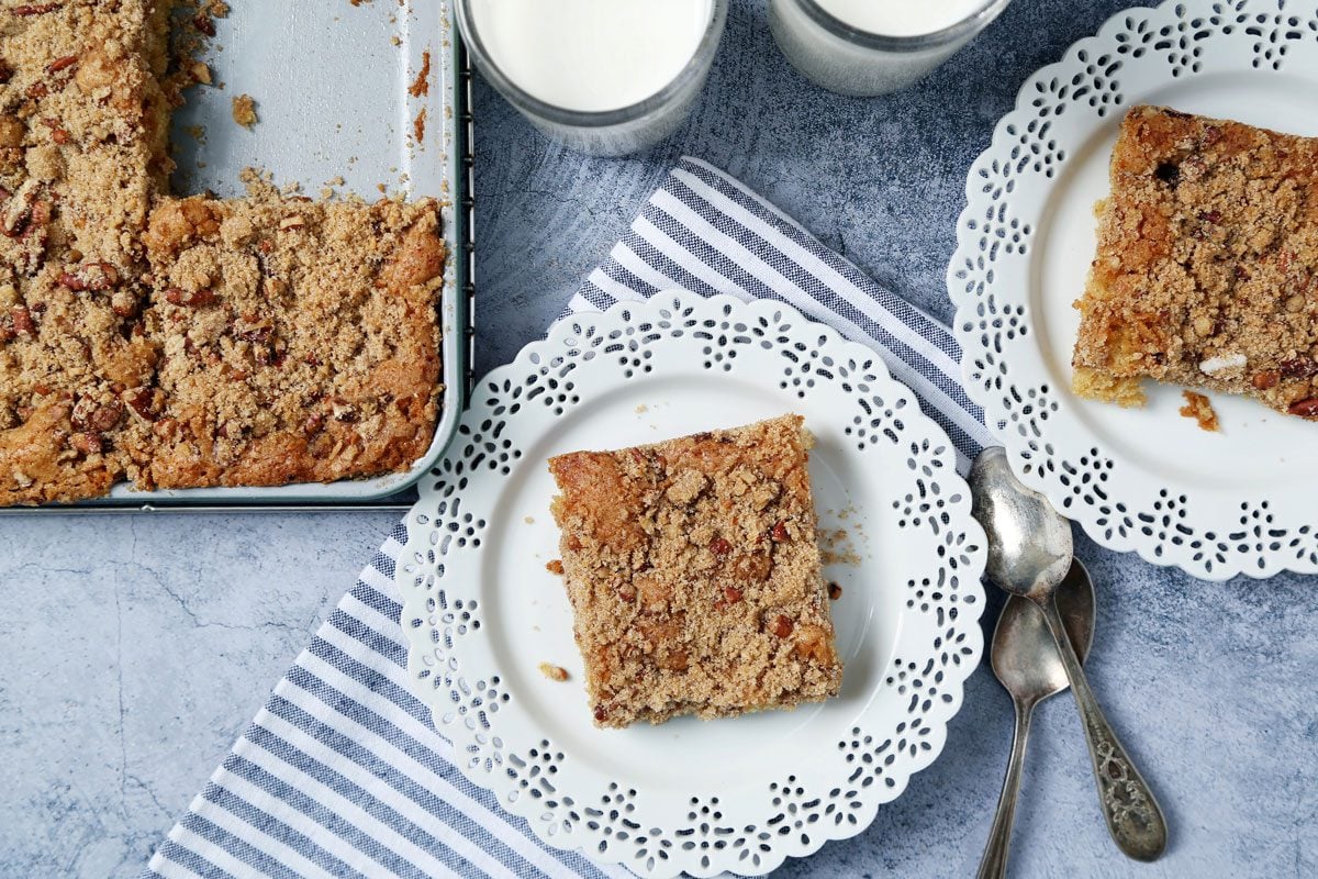 Close up of Taste of Home's Buttermilk Coffee Cake sliced and served on white plates on a light blue surface.