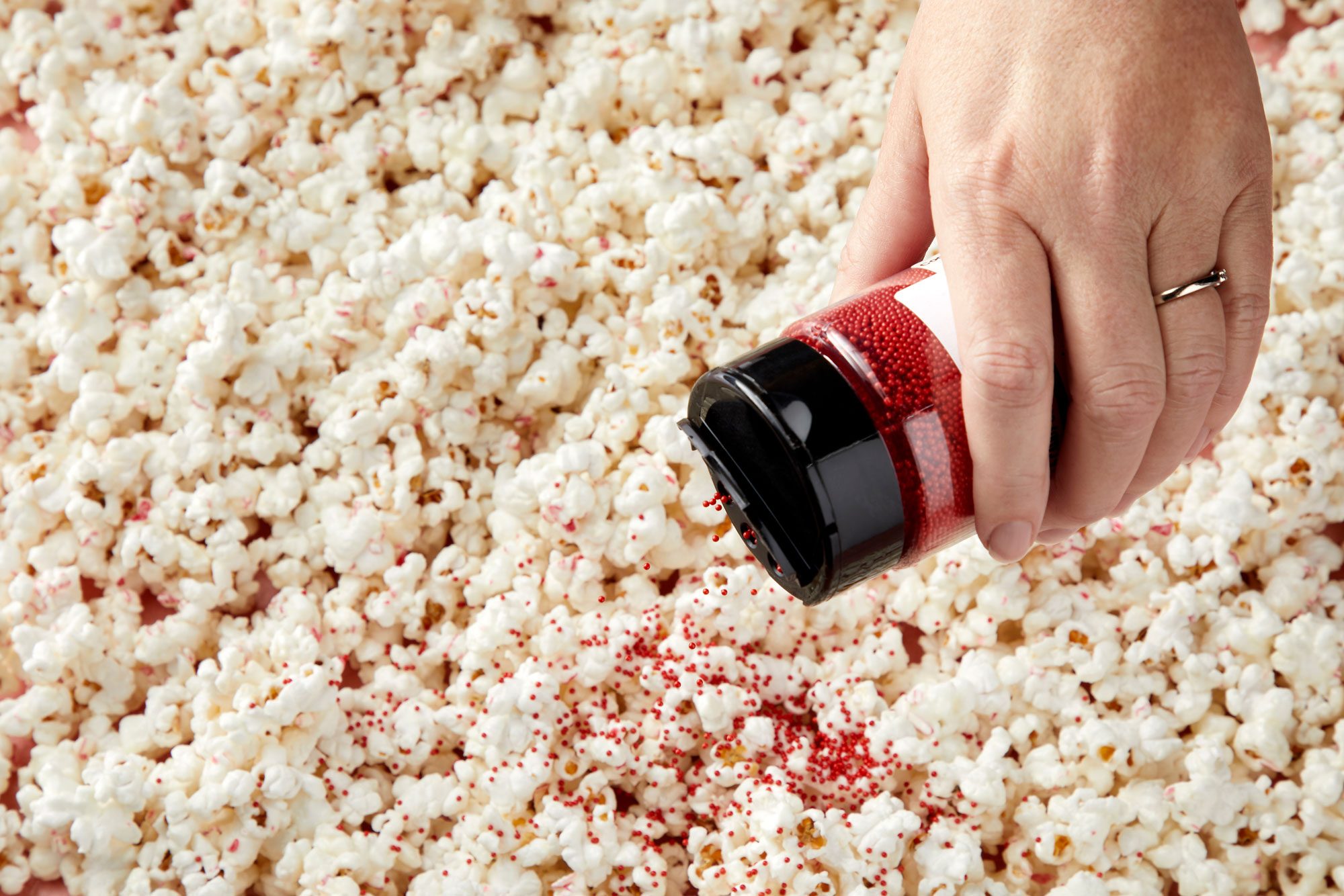 close up shot of sprinkling with nonpareils over popcorns