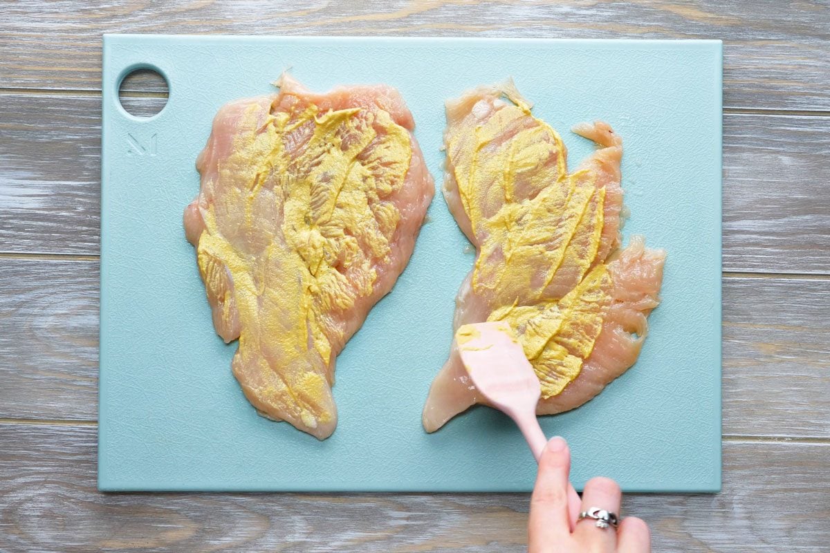 Spread 1-1/2 teaspoons mustard over 1 side of each chicken breast.