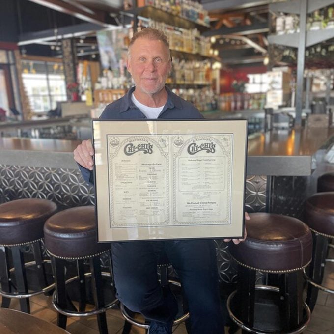 Michael McDermott, Founder of Chi-Chi's Restaurants, Poses with the Chi-Chi's Menu
