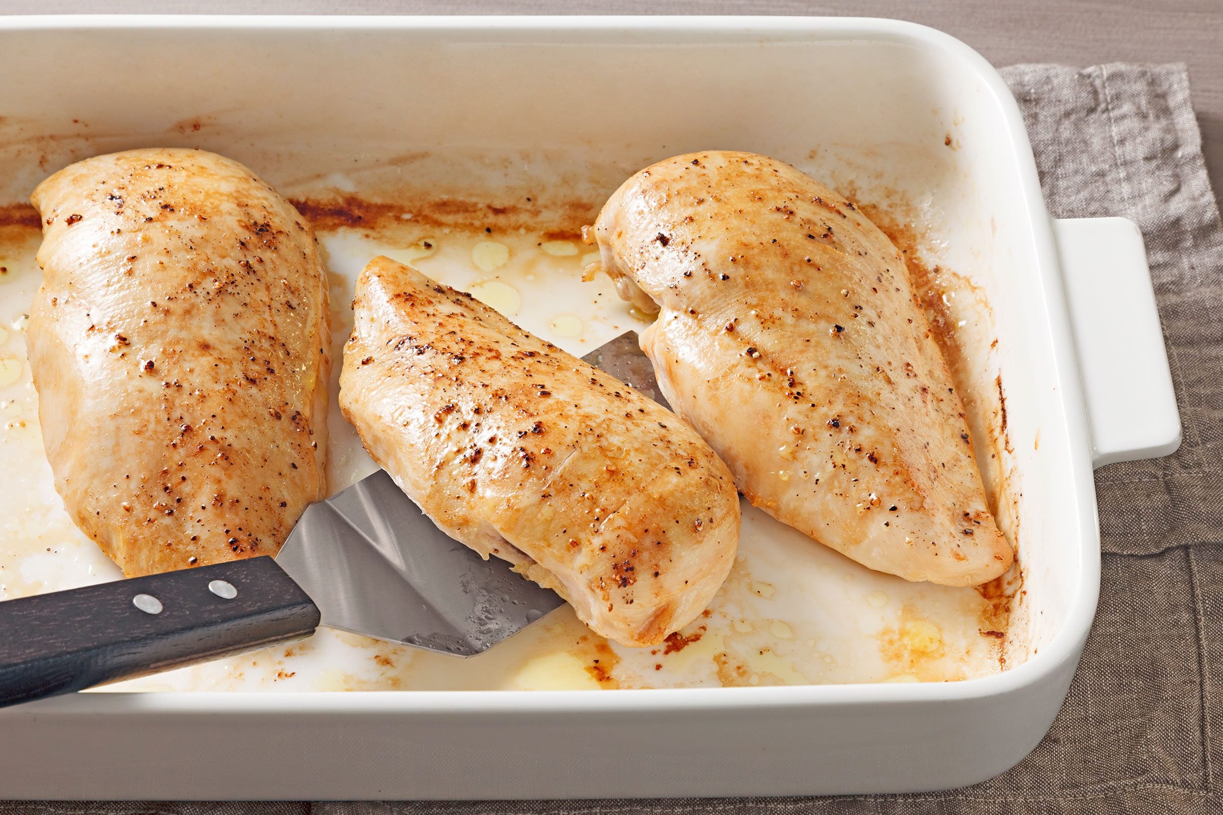 Seasoned Chicken Breasts baked in oven in a greased sheet pan