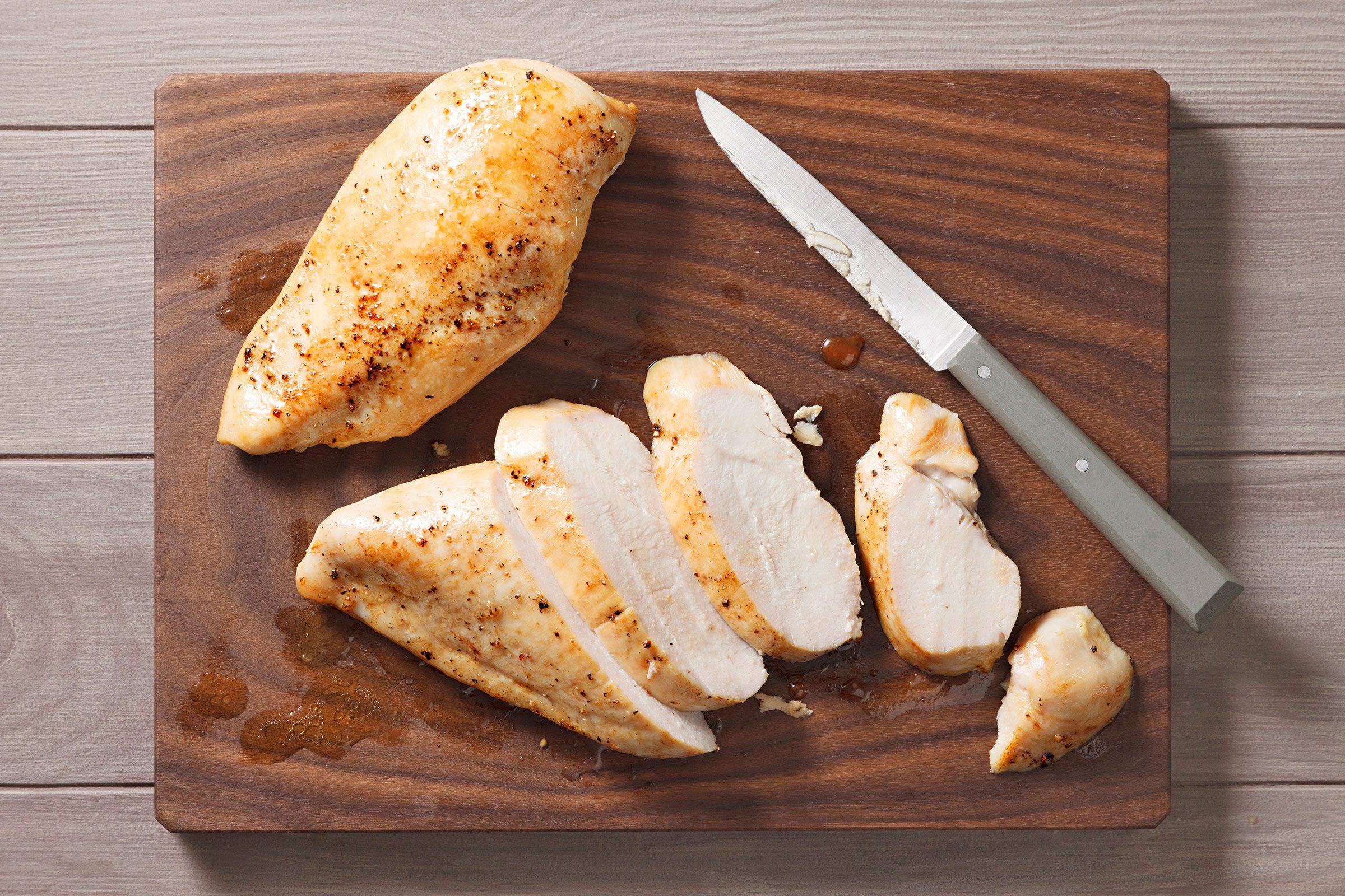 Chicken Breasts chopped into pieces on a wooden cutting board with a knife