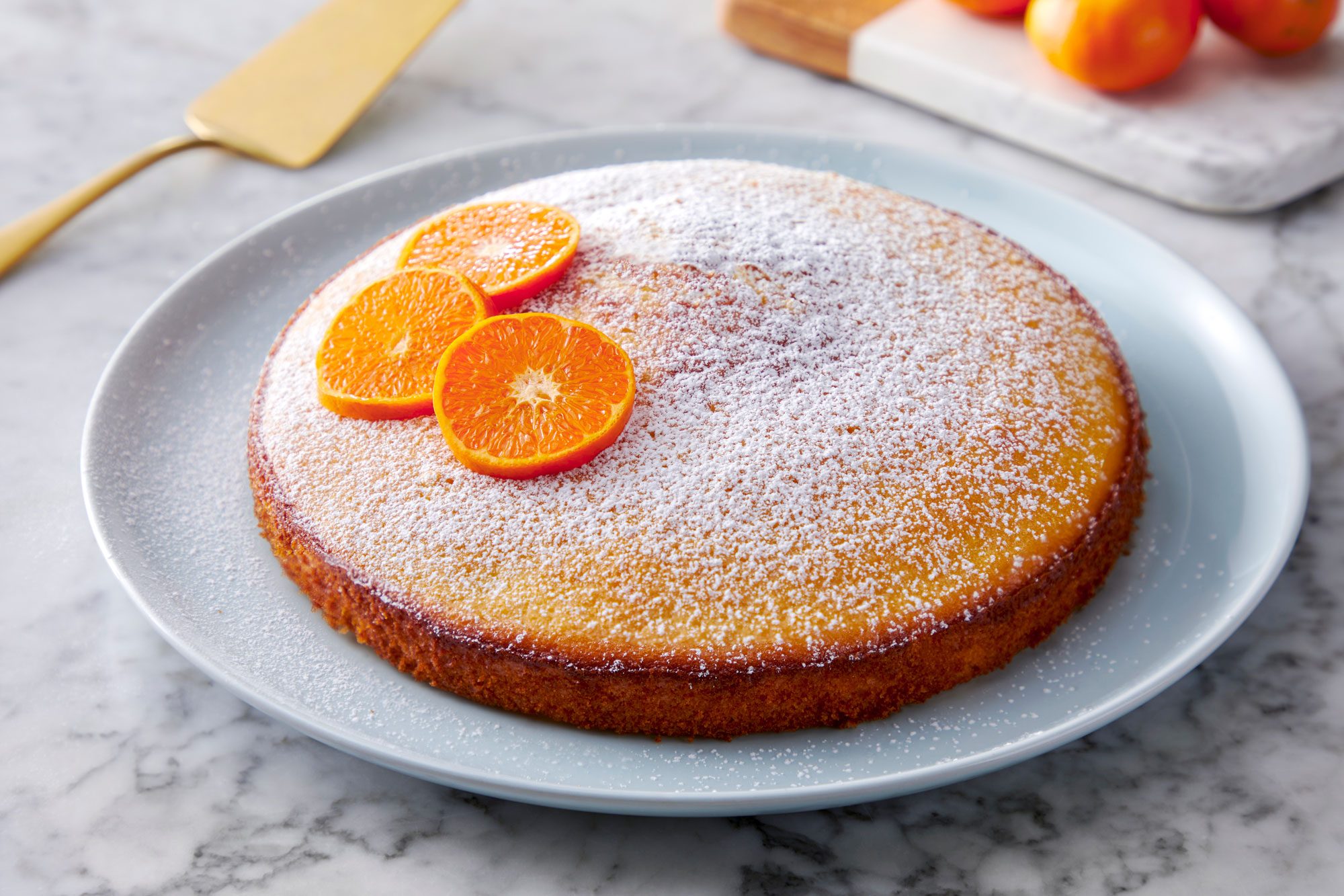 Orange Olive Oil Cake served in a plate with sugar sprinkled with orange slices on top