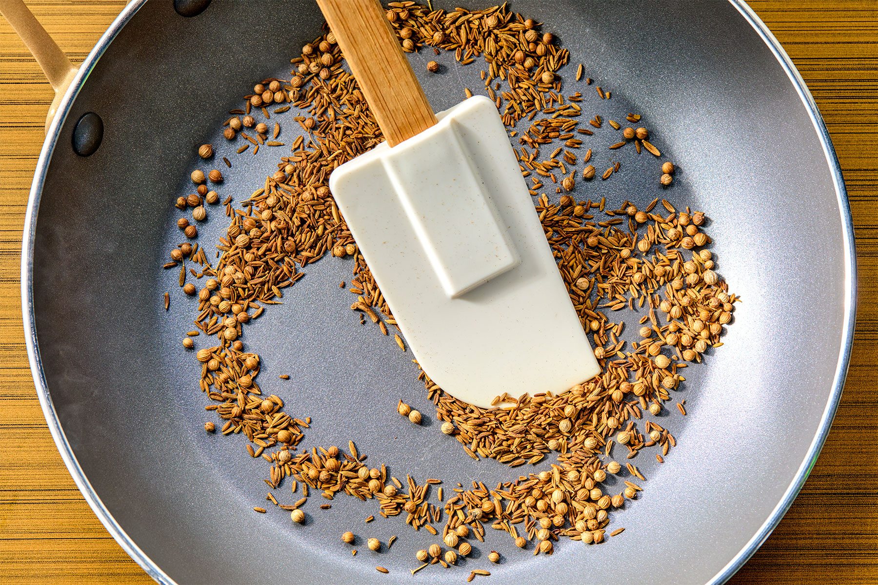 overhead shot of Toasting cumin and coriander seeds until seeds have darkened, stirring frequently
