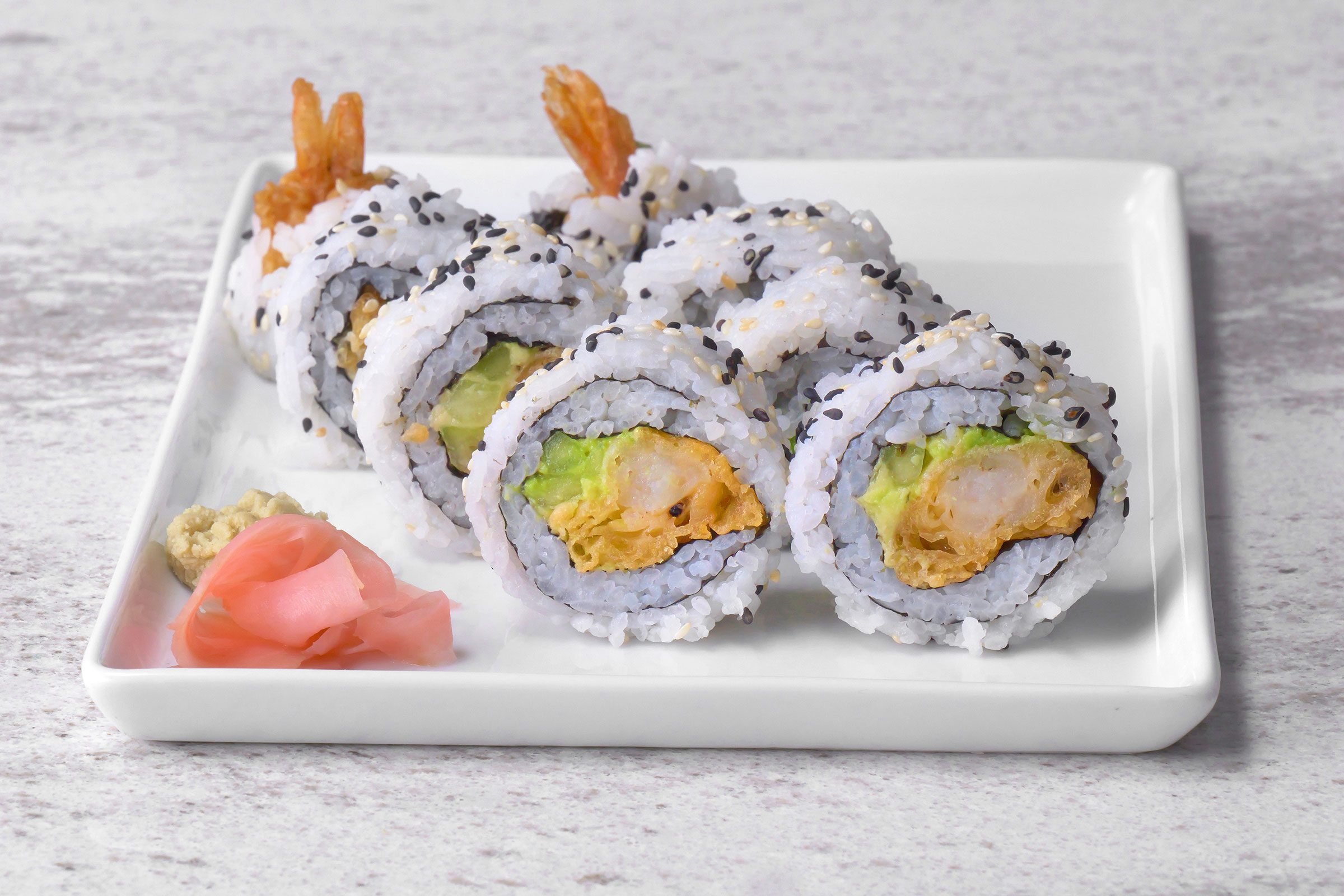 Shrimp Tempura Roll cut into pieces served on a white plate