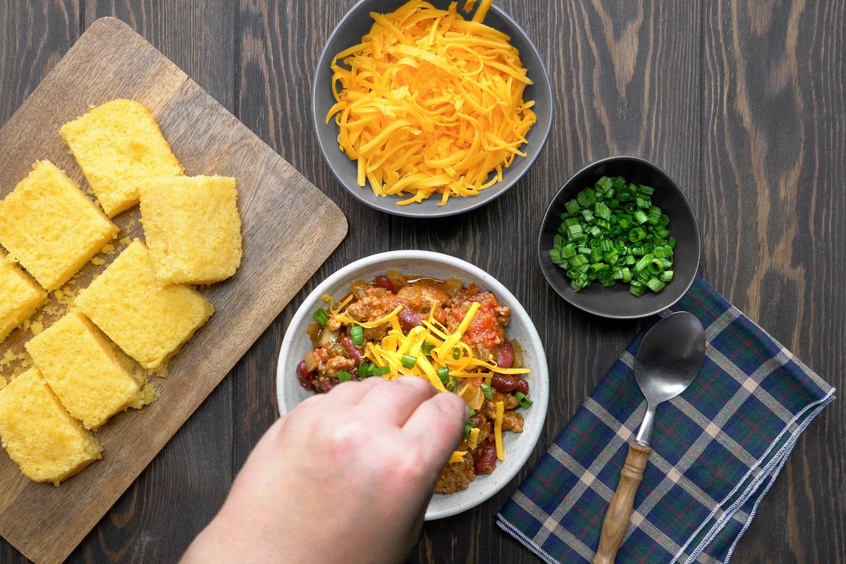 chill being topped with cheese and green onions