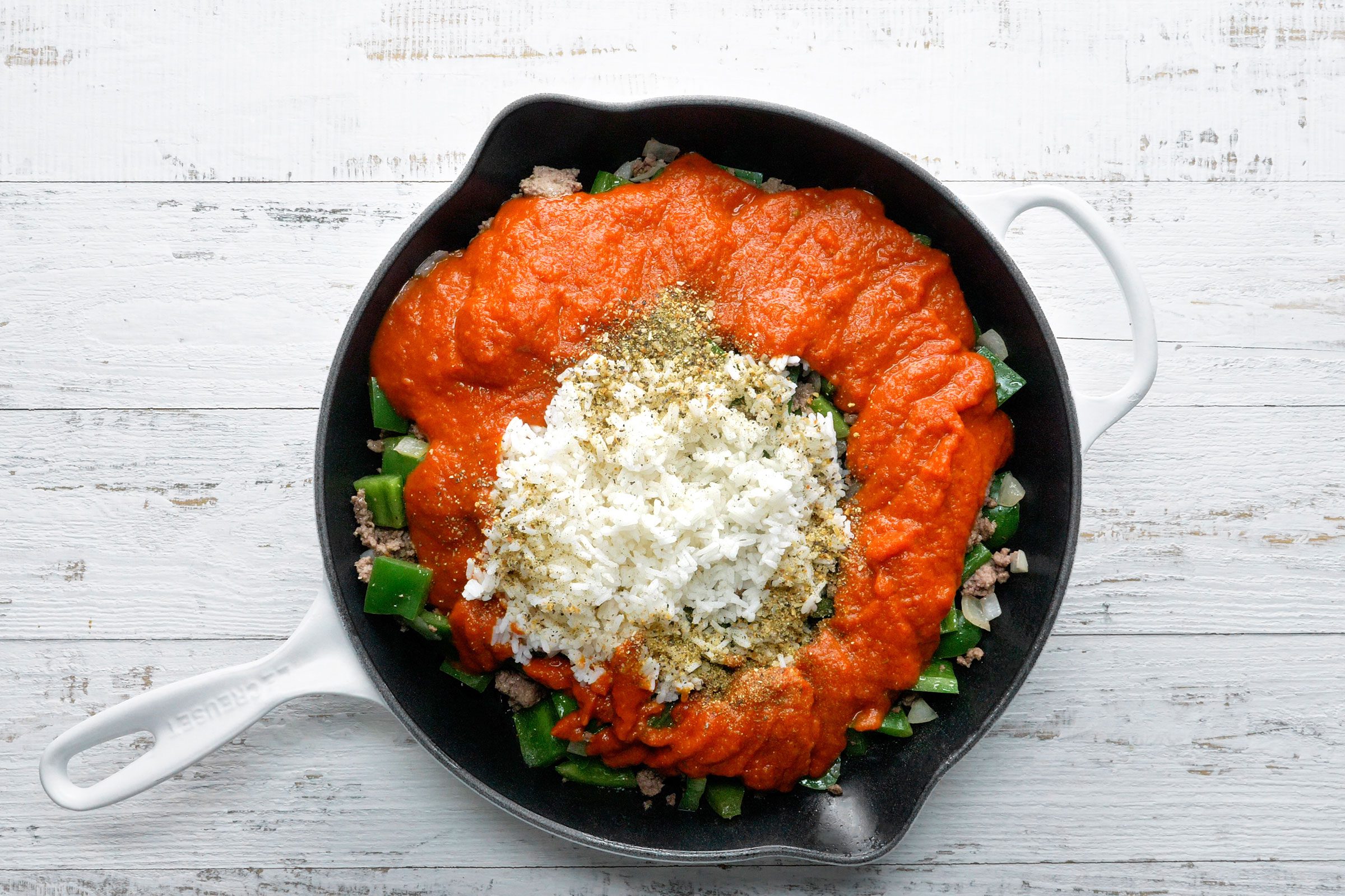 Rice, marinara sauce and seasonings added to cooked beef and green peppers in a large skillet