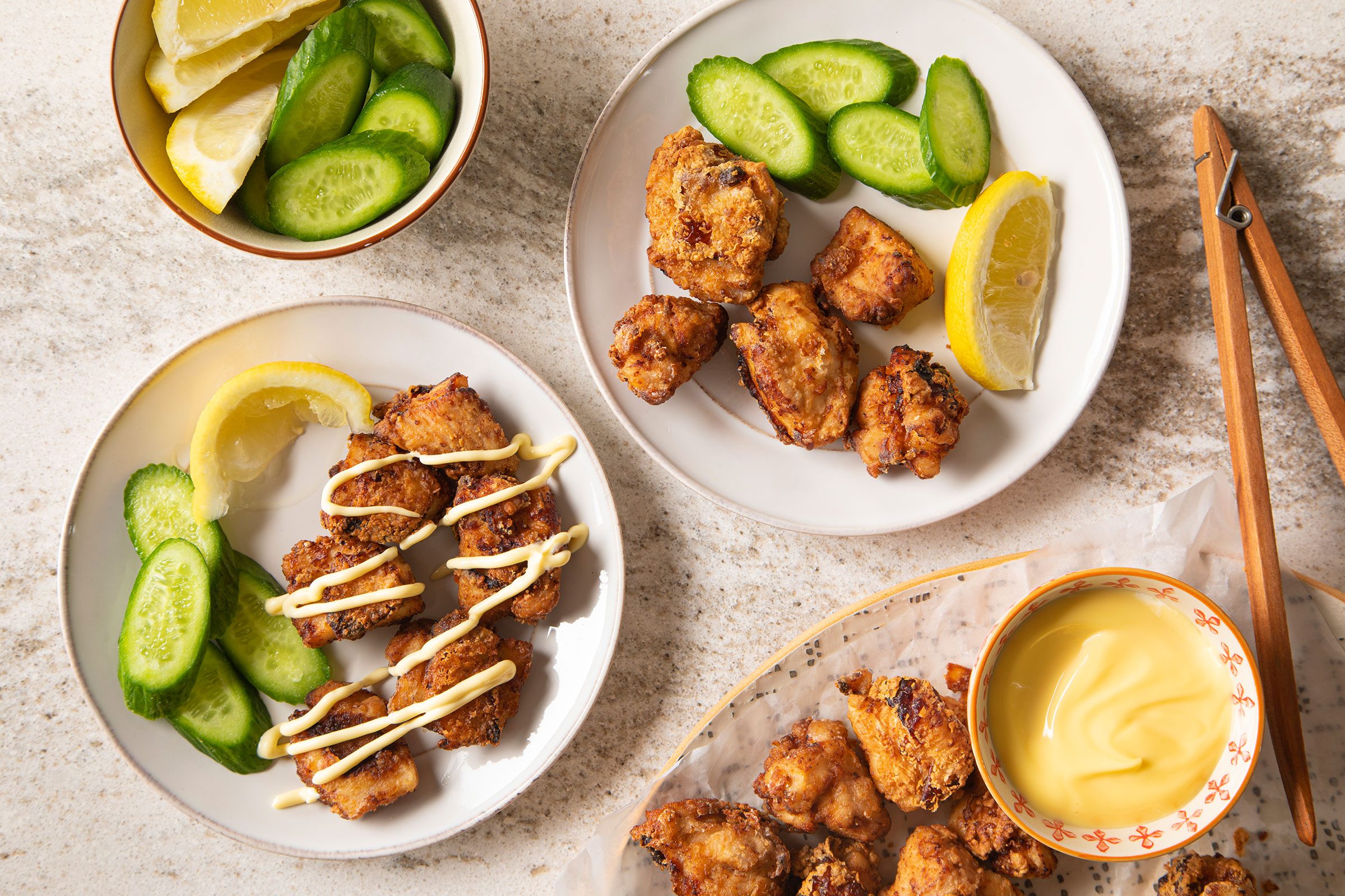 Japanese Fried Chicken (chicken Karaage) served on white plates with cucumber and lemon