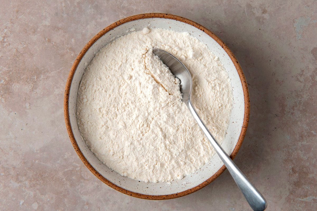 Top view shot of Homemade Self-Rising Flour; in a bowl with spoon; marble surface;