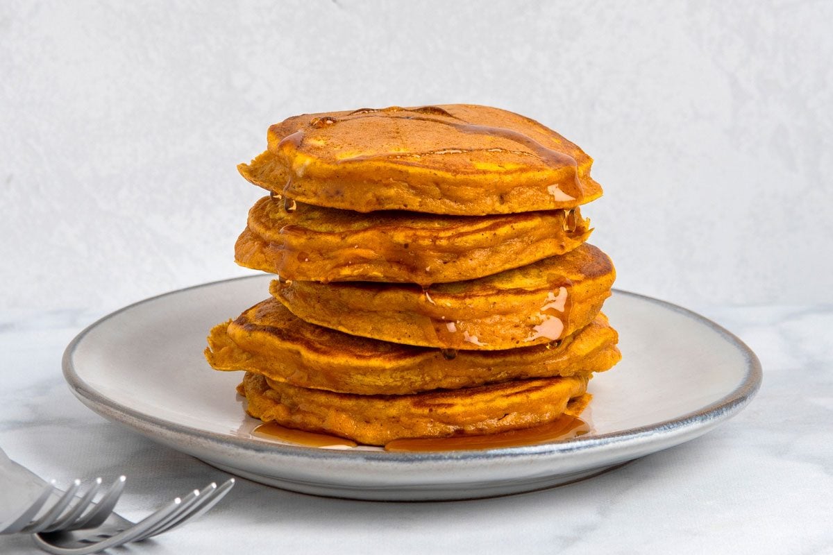 Table view shot of Fluffy Sweet Potato Pancakes; served on plates; with syrup; forks; marble surface;
