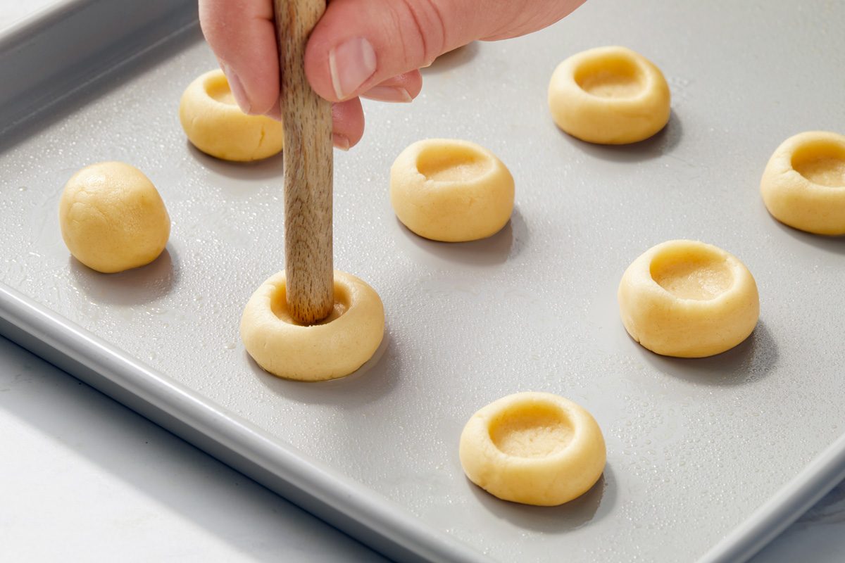 indentation being pressed into centre of dough ball with wooden spoon handle