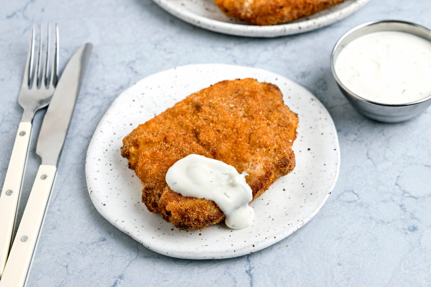 Air Fryer Pork Schnitzel is ready and served in a plate with sour cream.