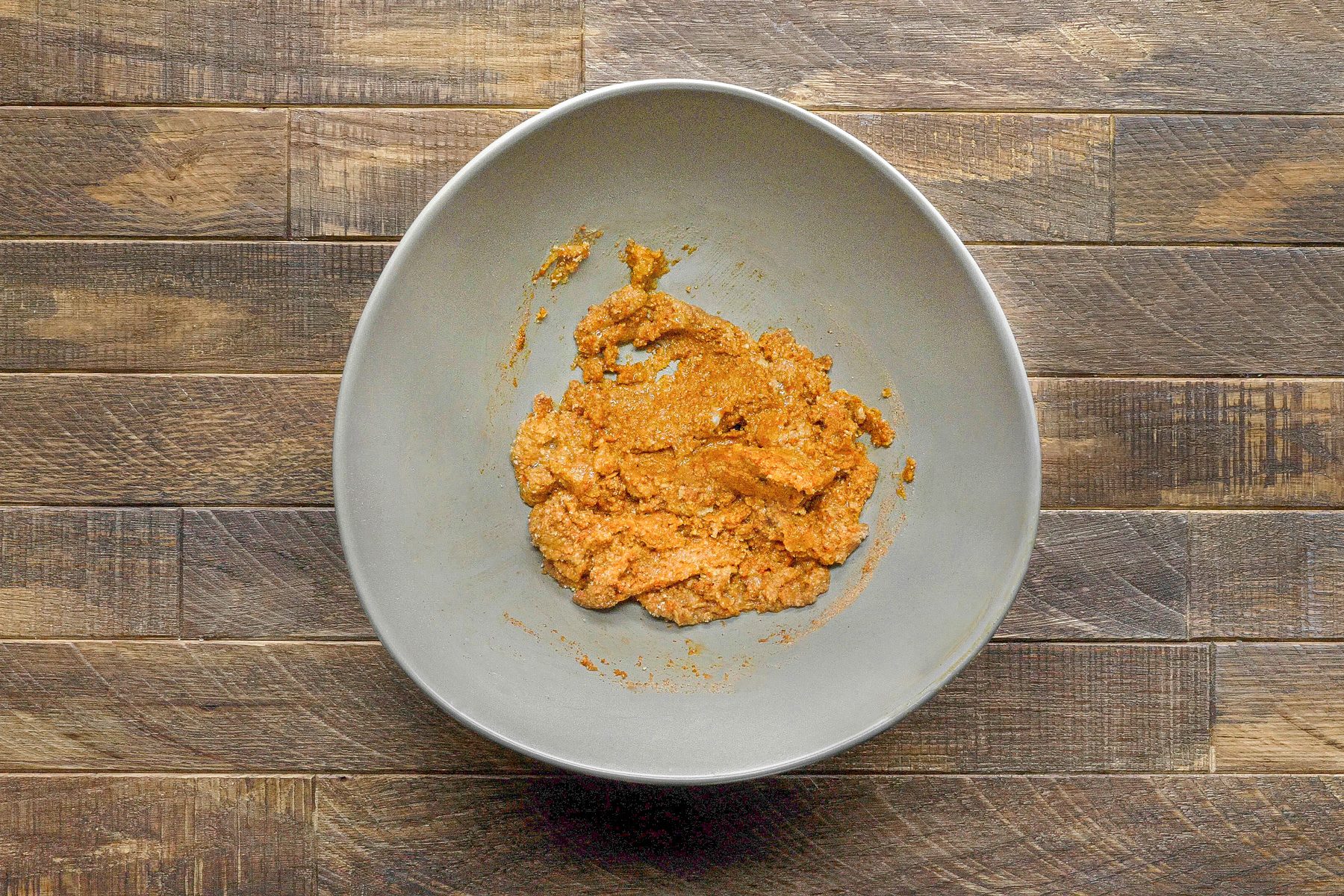 overhead shot of a gray oval-shaped bowl with a brown mixture inside it; the bowl is sitting on a wooden surface