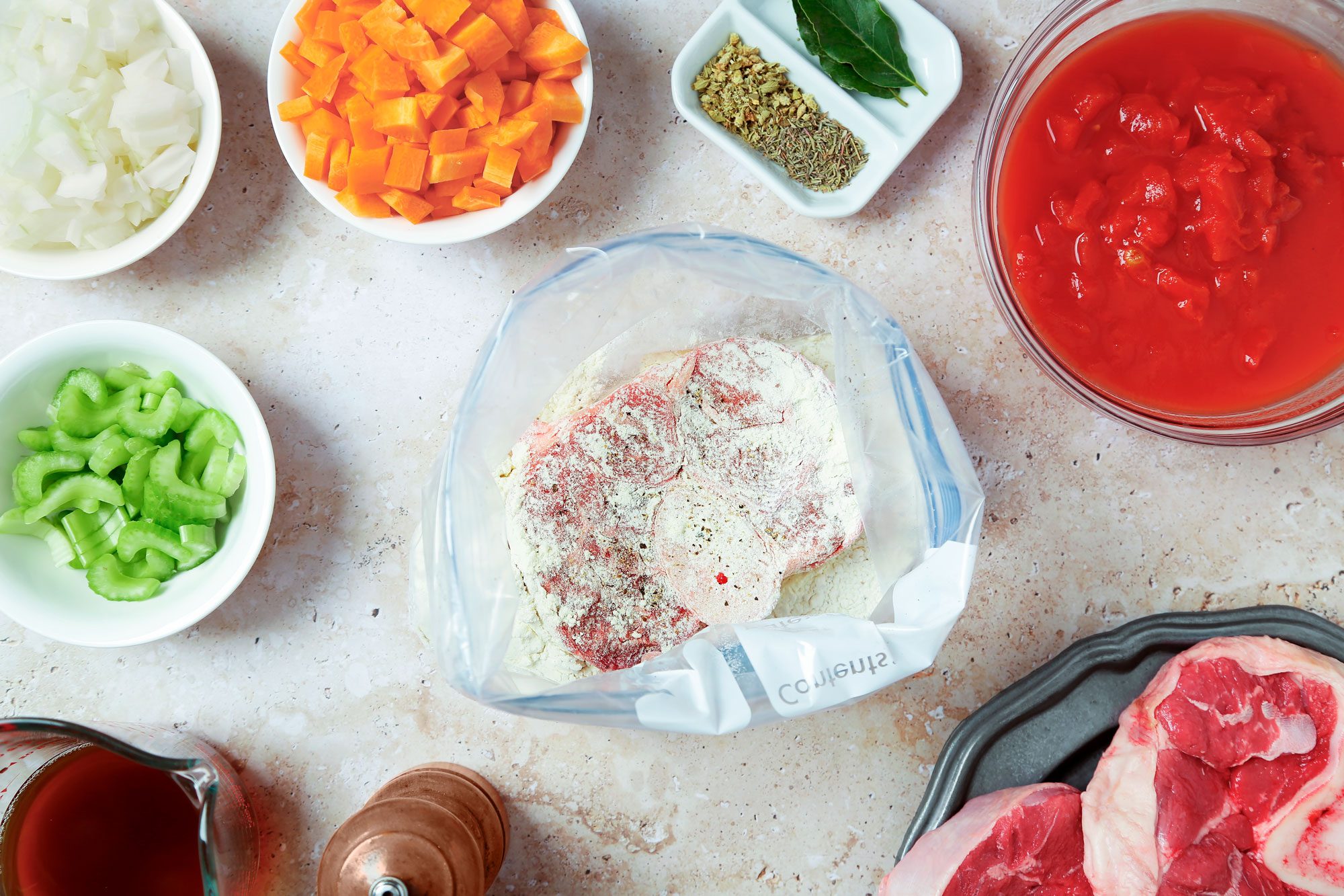 overhead shot of Osso Buco ingredients placed on a beige marble surface