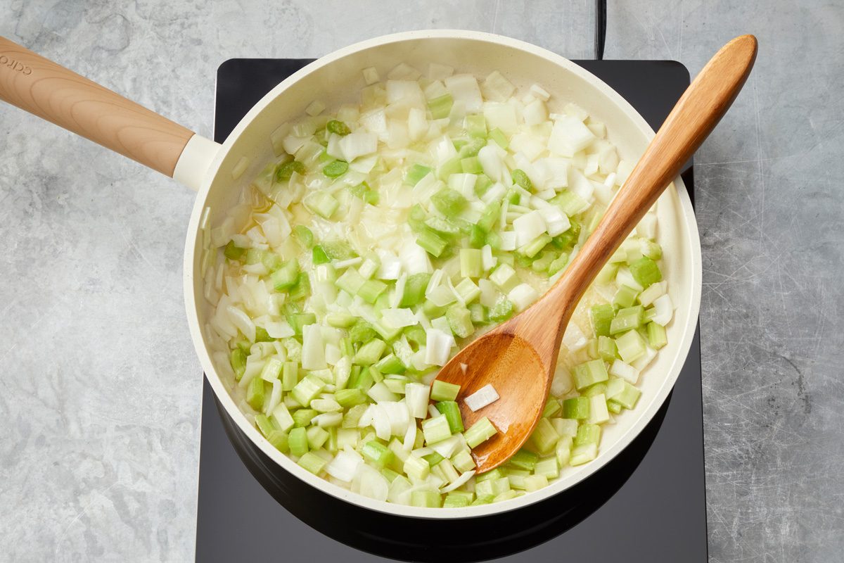 Overhead shot of add butter; cook onion and celery until crisp-tender 3-5 minutes; woodens poon; marble surface