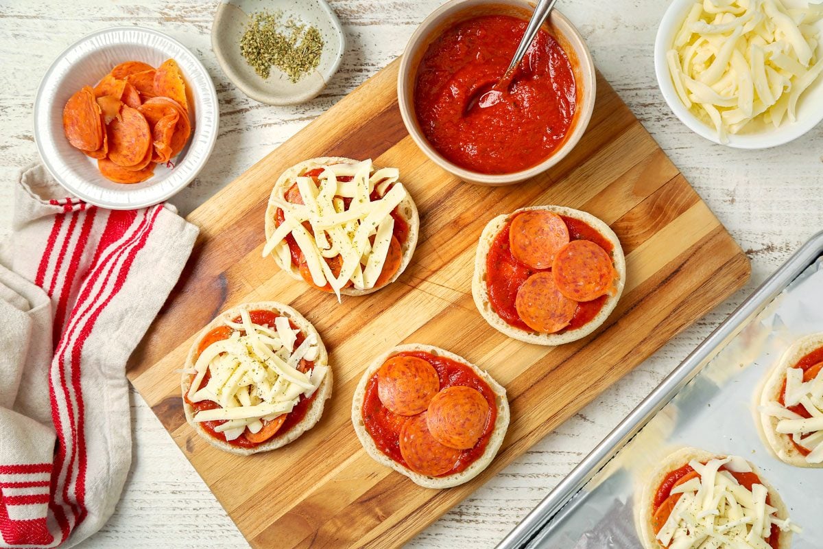 English Muffin Pizzas assembled on a wooden board.