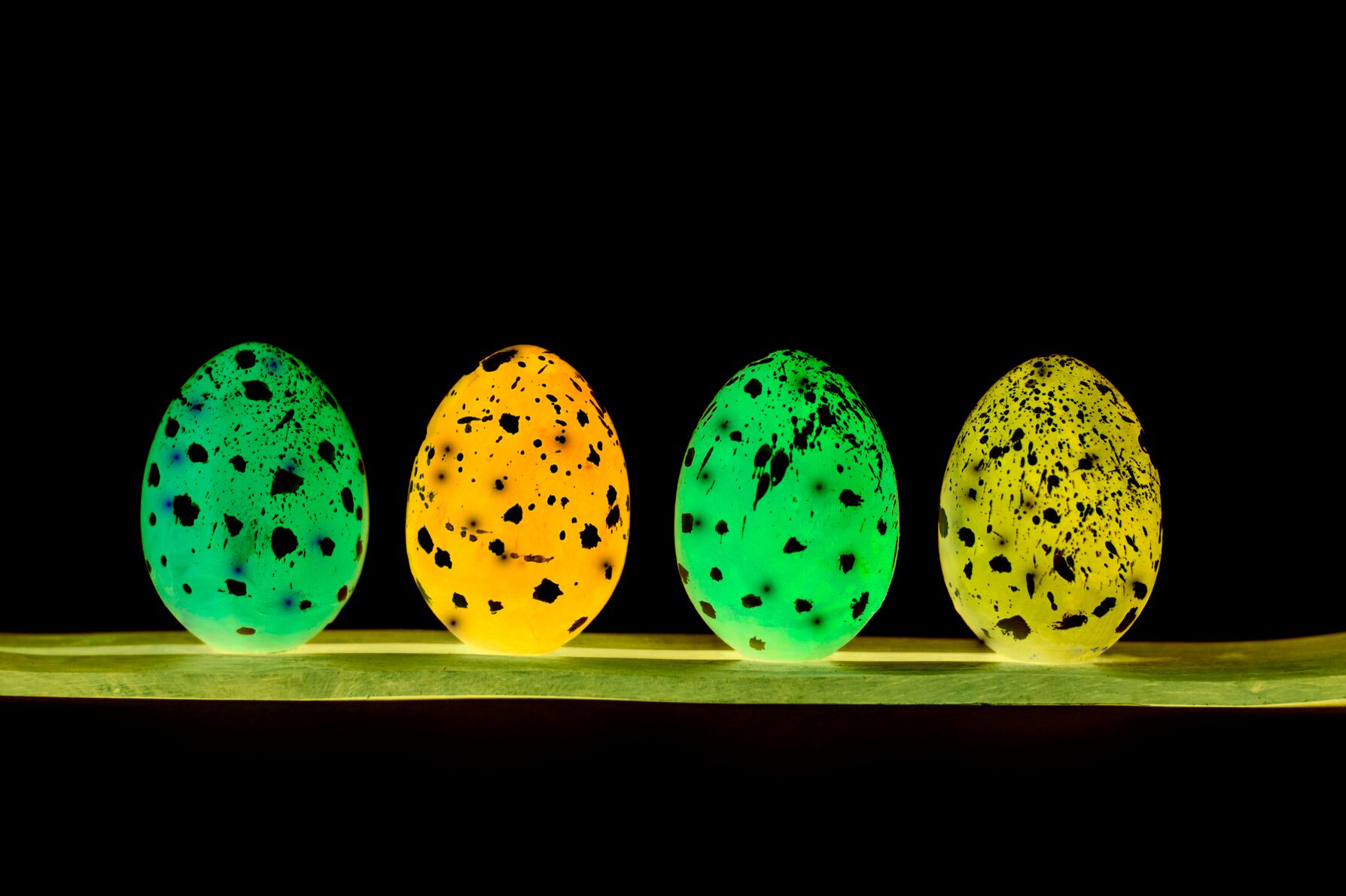 On a black background, Easter eggs glow in neon.