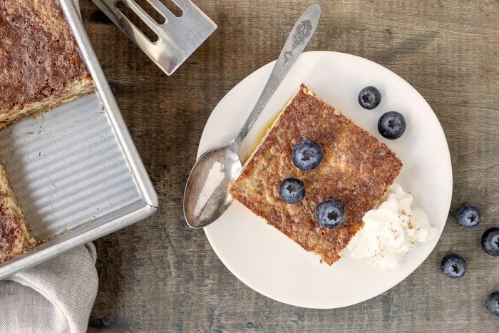 Grape Nuts Pudding served in a plate with whipped cream and grapes over it with spoon