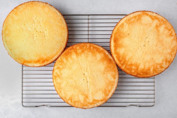 Baked lemon cakes on a wired rack kept on top of a grey marbletop