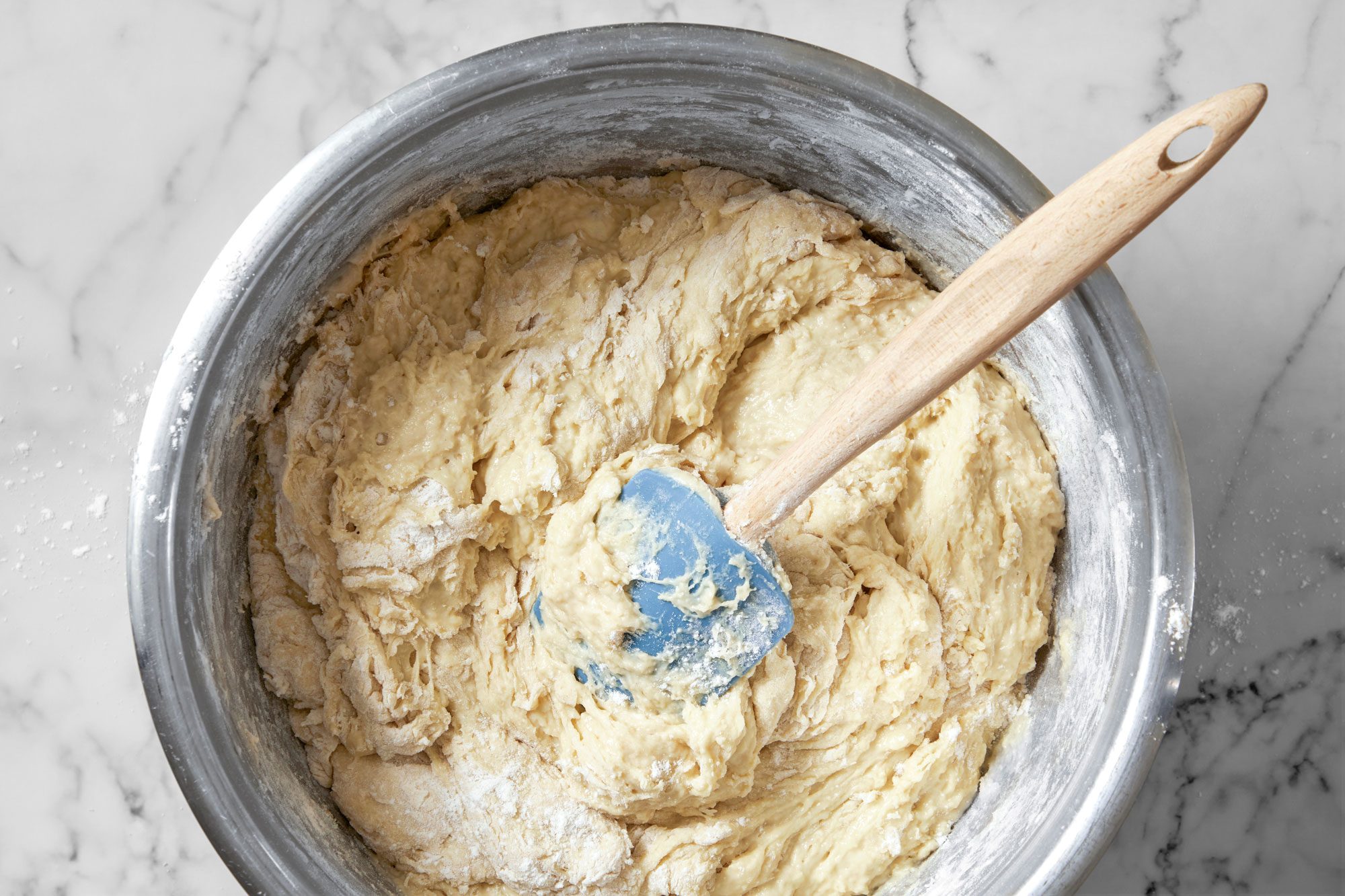 Overhead shot of stir in enough remaining flour to form a soft dough; spatula; marble surface