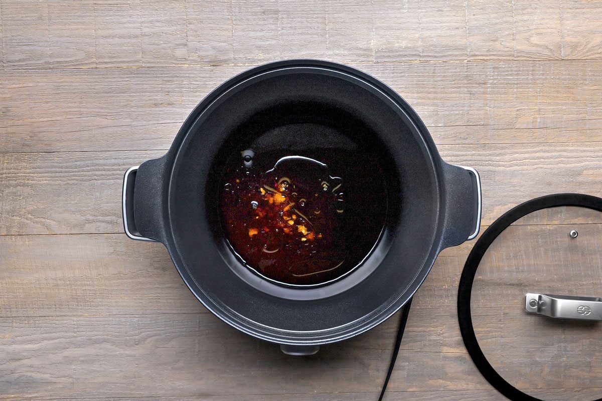 overhead shot of a black pot with a glass lid on a wooden surface