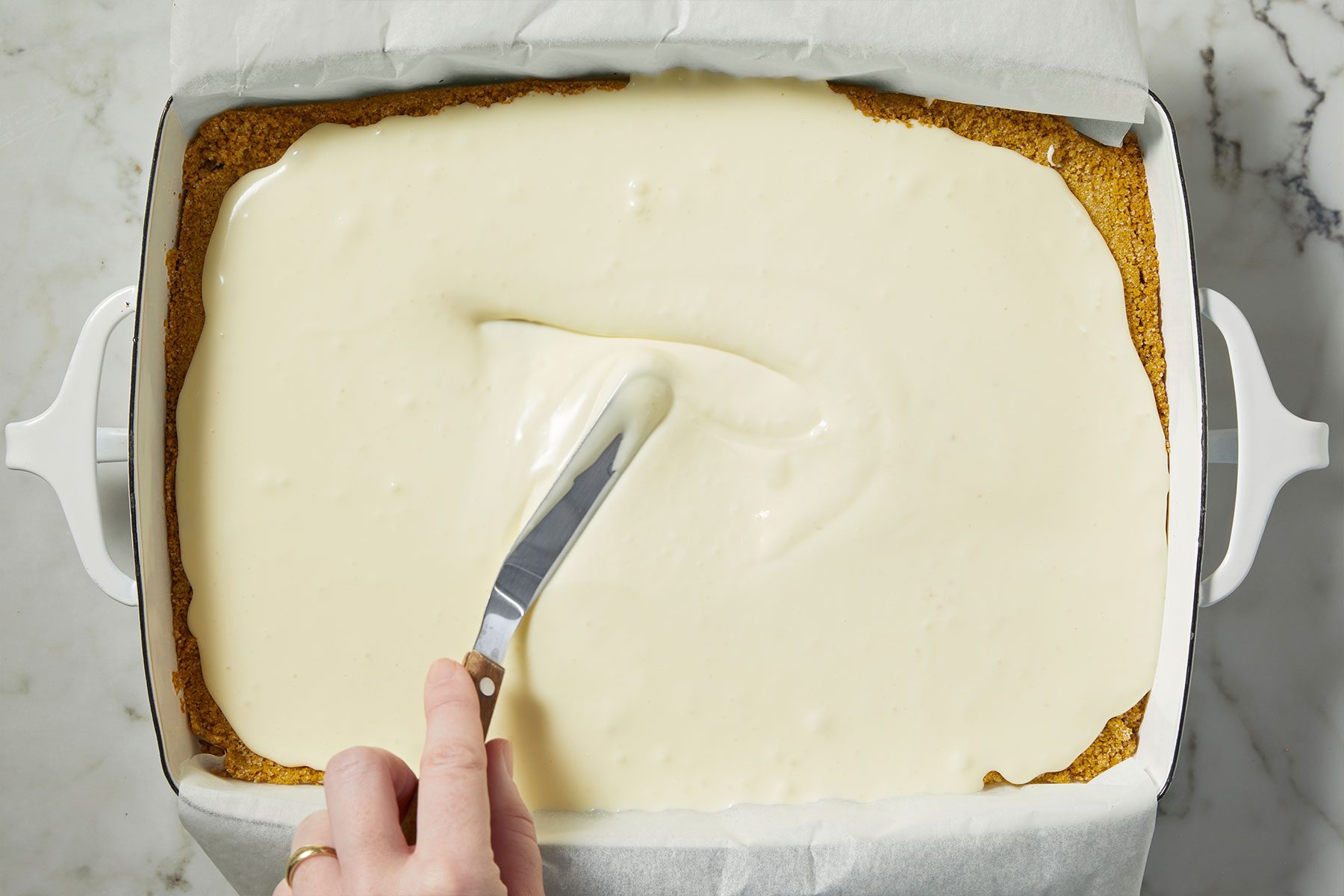 Applying cheesecake filling on chilled crust for Strawberry Cheesecake Bars