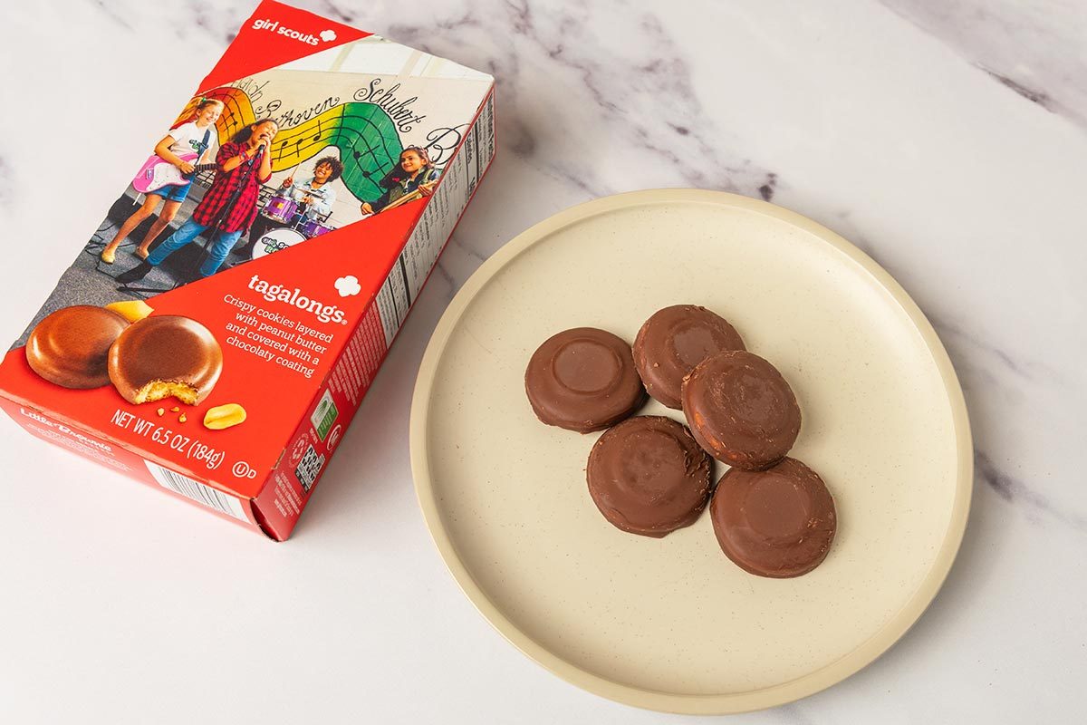 Package of Tagalongs Girl Scout Cookies next to several cookies on a plate