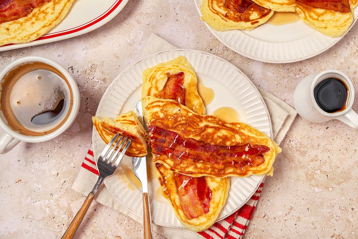 Bacon pancakes served on white plate with maple syrup