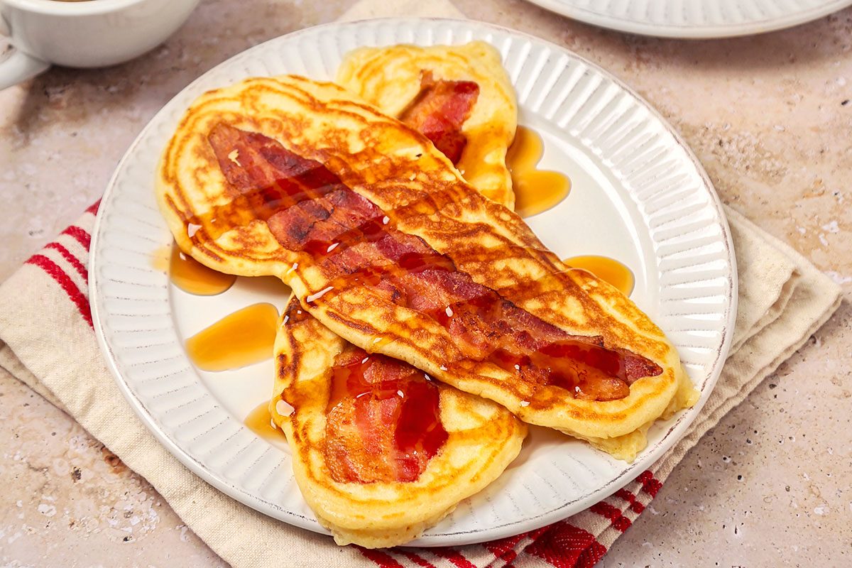 Bacon pancakes served on white plate with maple syrup