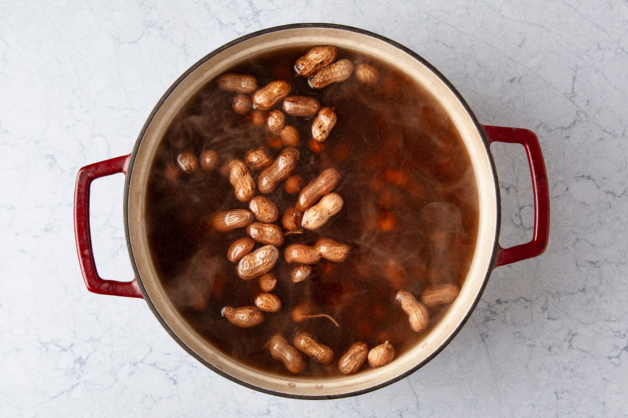 Overhead shot of place water; salt and peanuts in a large stock pot; bring to a boil; reduce heat to medium-low; Simmer covered until peanuts are tender 2-3 hours; marble surface;