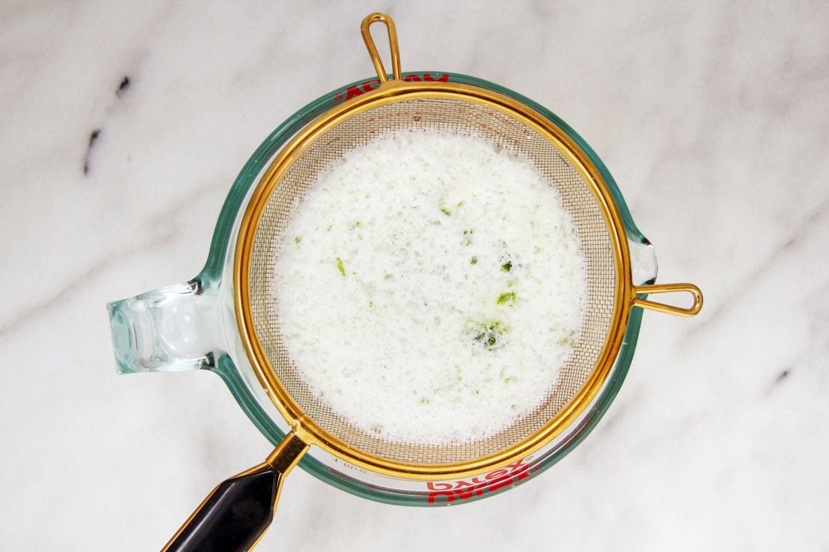 Top view of a clear measuring cup with a fine strainer resting on it.