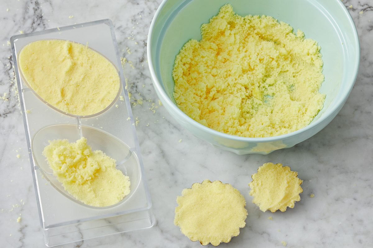 bowl of sugar mixture next to egg half and tart moulds filled with mixture