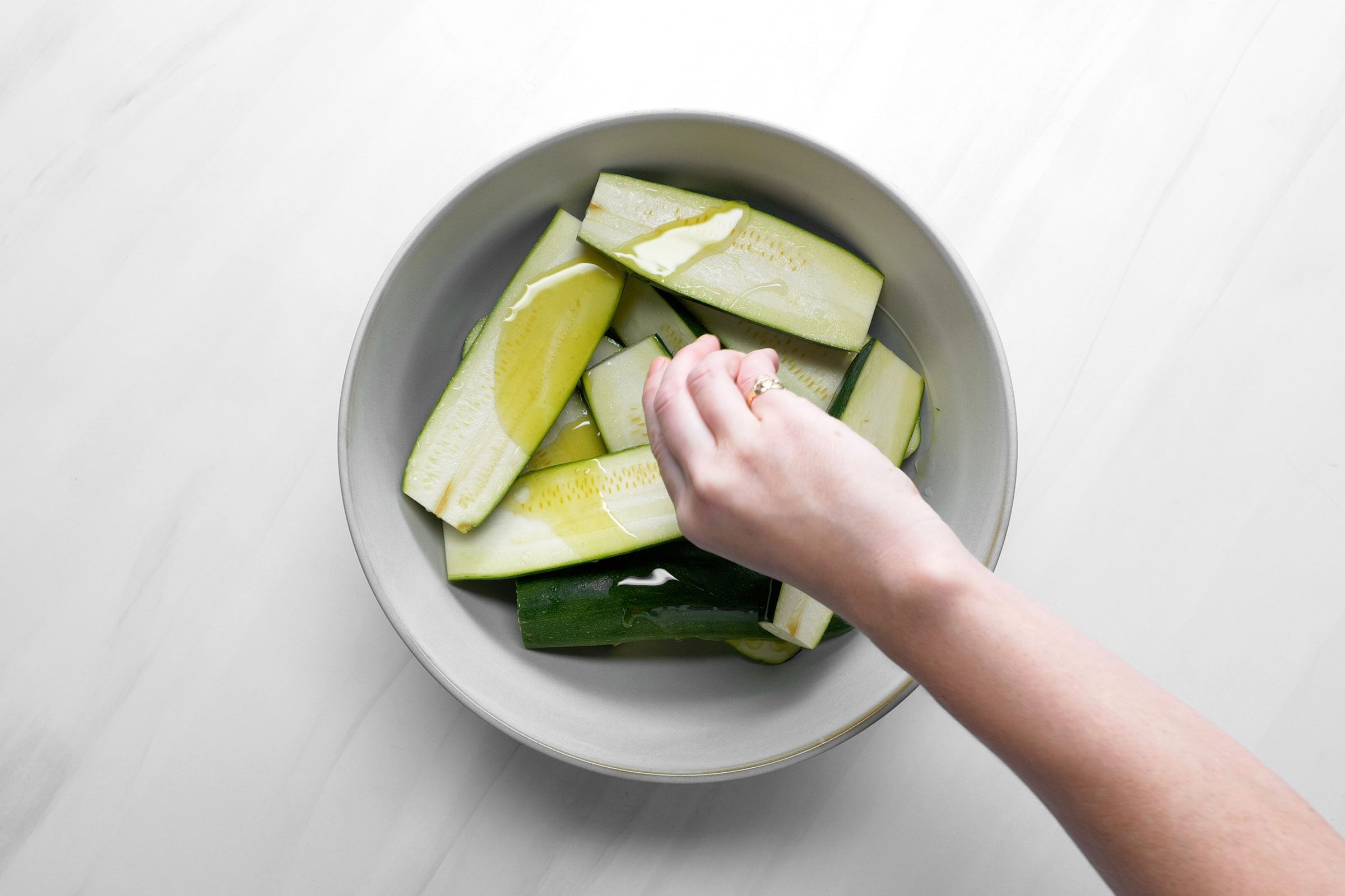 Drizzling the sliced zucchini with 2 teaspoons oil