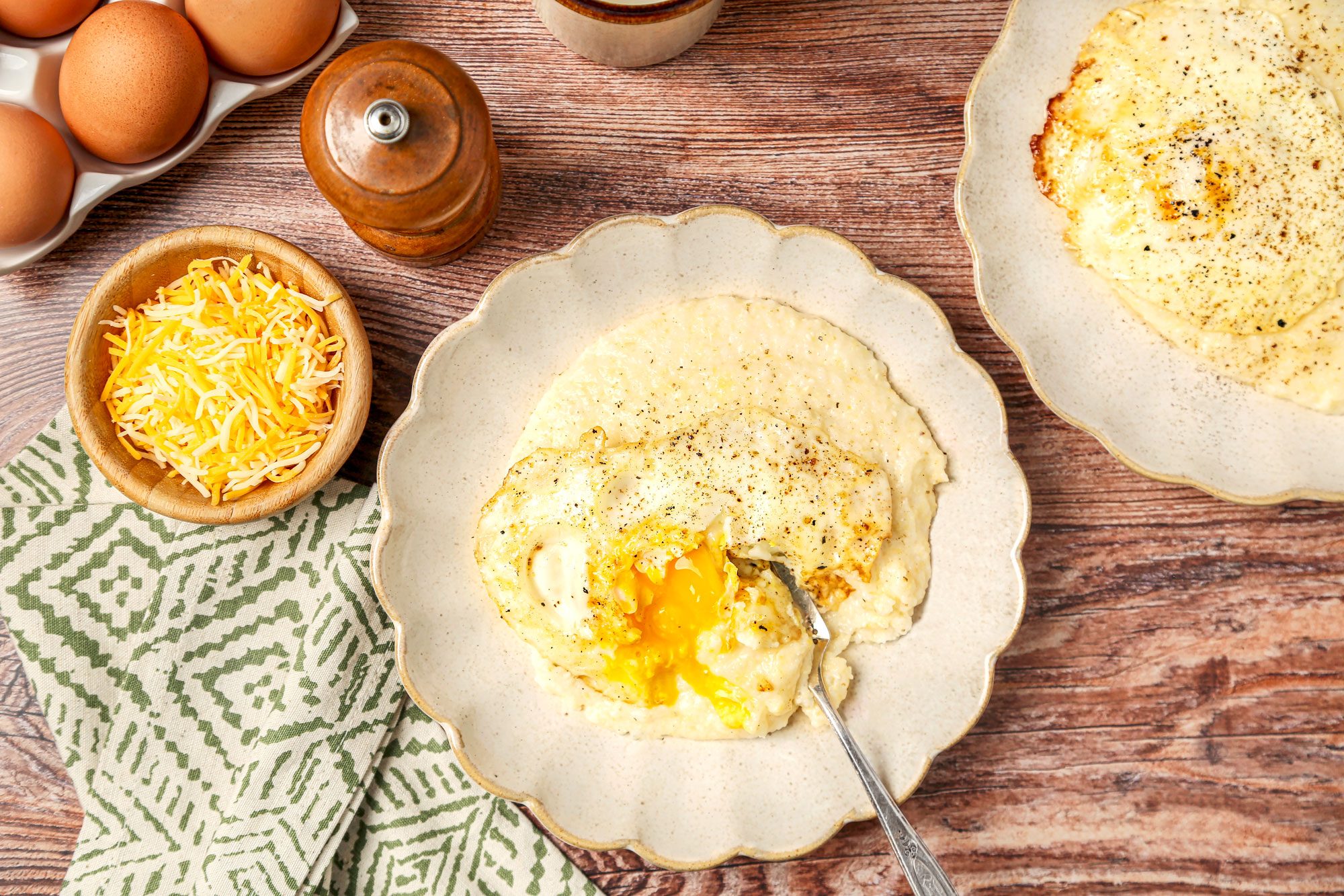 Grits served on plates with eggs on top and black pepper