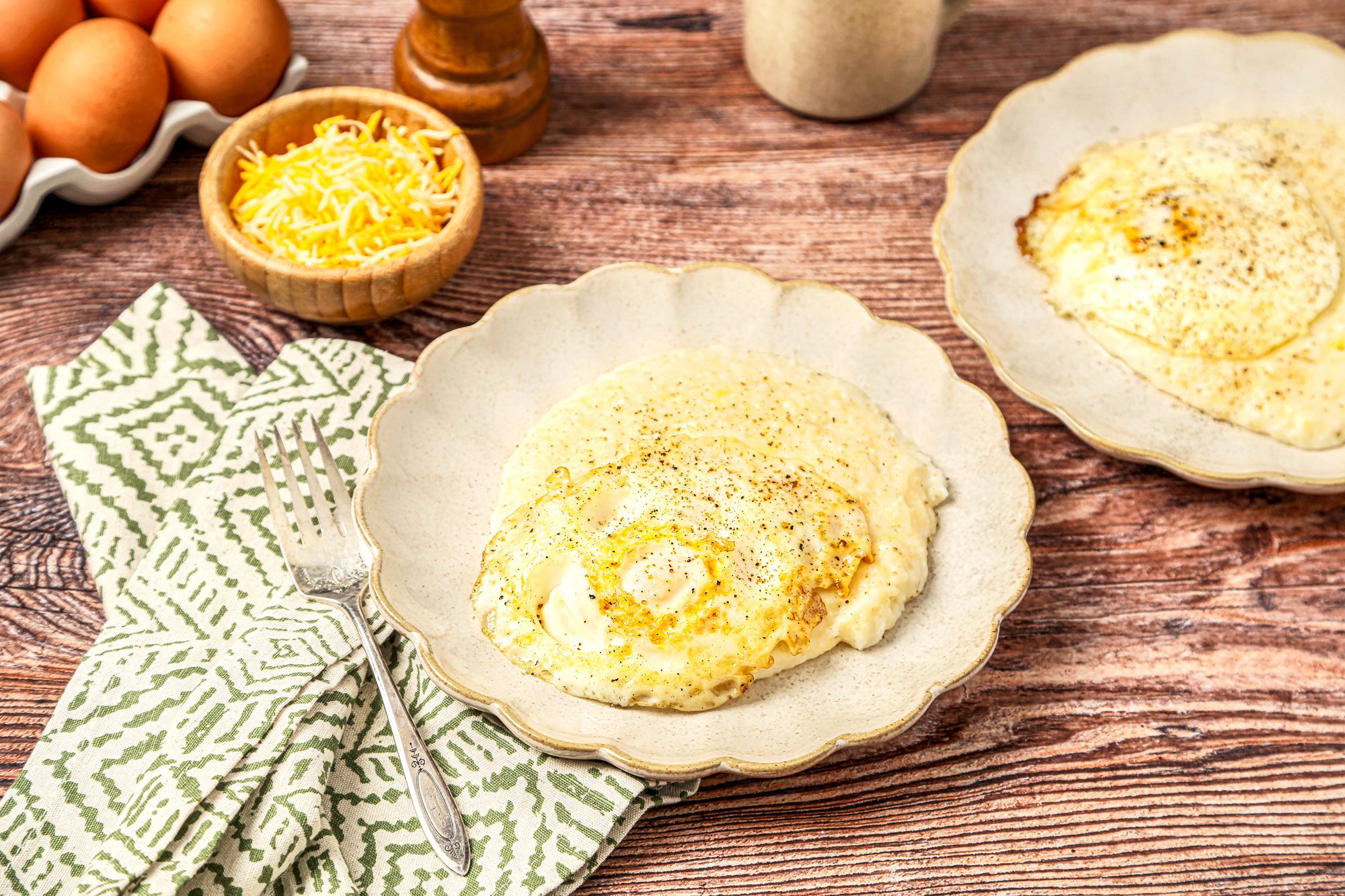 Grits served on plates with eggs on top and black pepper