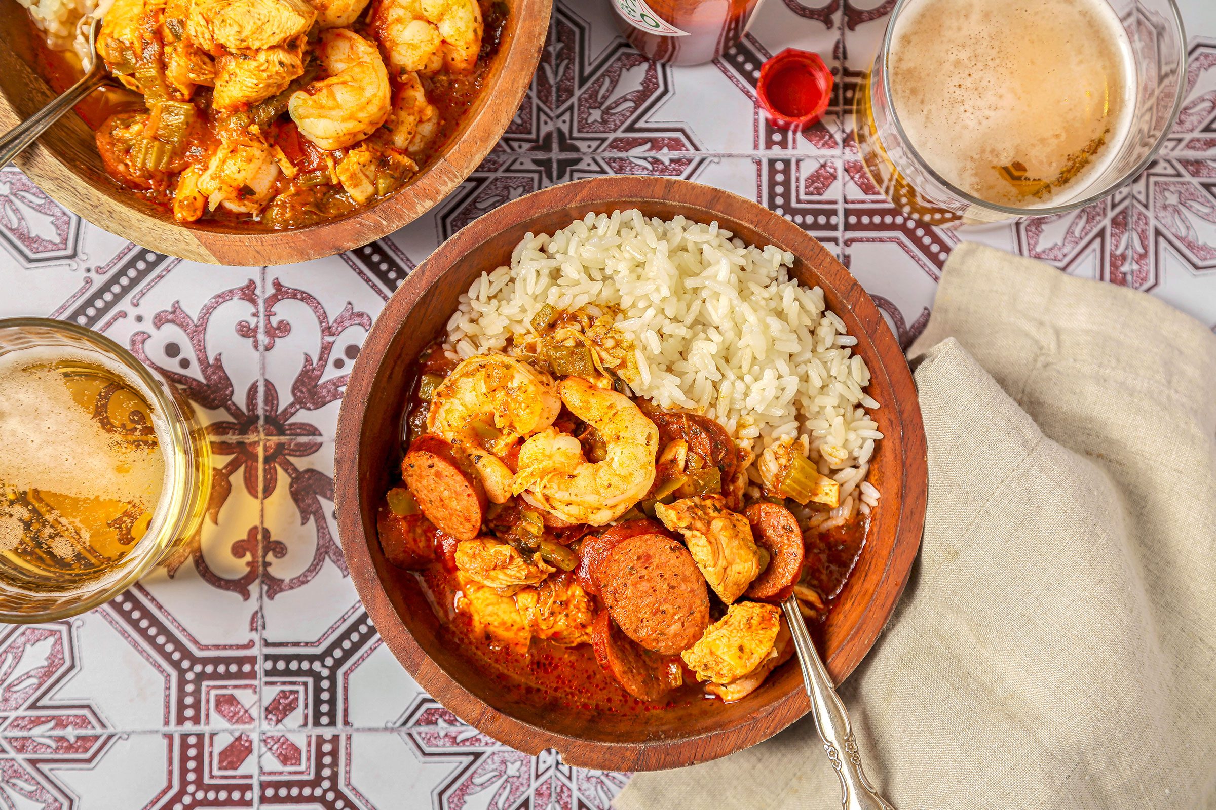 Jambalaya served with rice in a dish on colorful kitchen table with beverages on side
