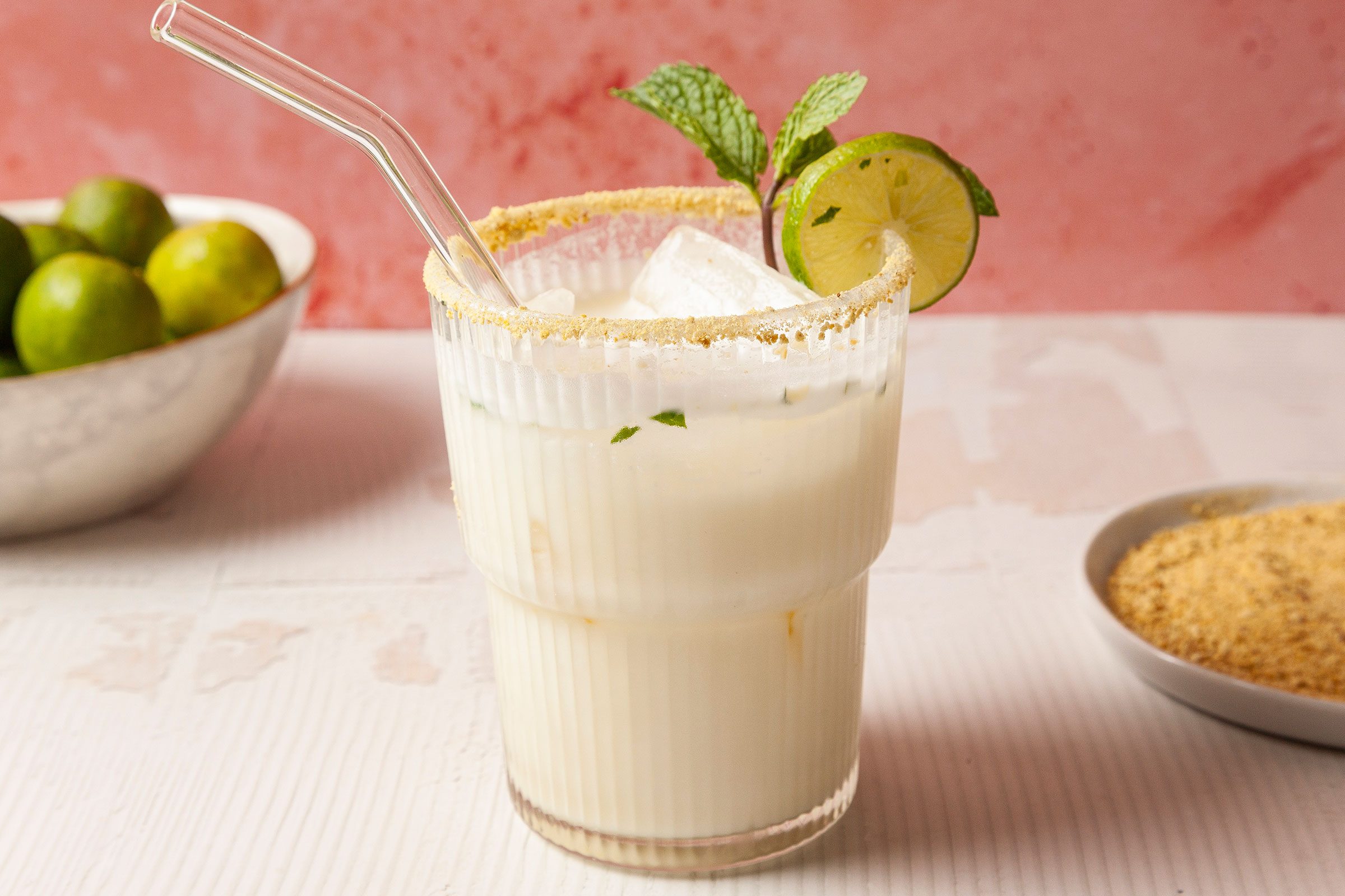 Key Lime Mojito in a glass with a glass straw and slice of lemon and few mint leaves