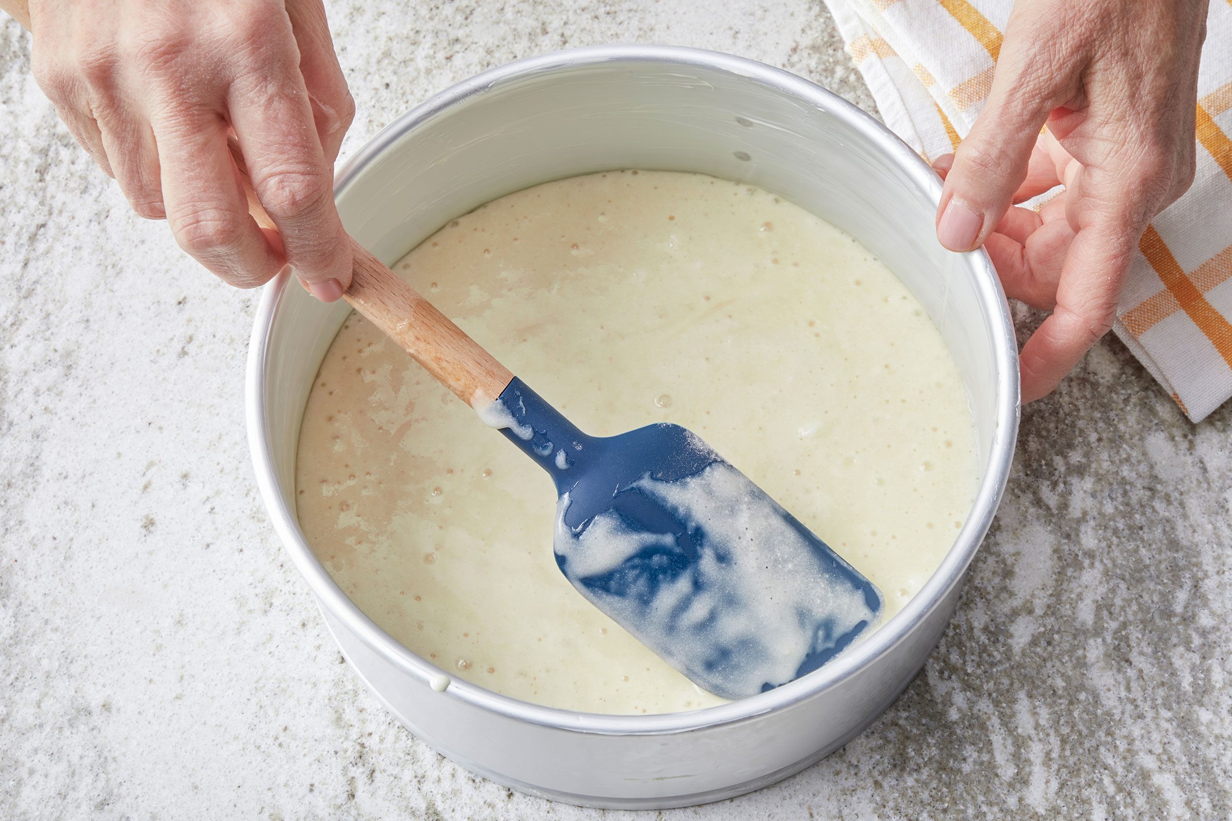 Pouring the batter into a greased 8-inch springform pan and smoothing the top with a mini spatula