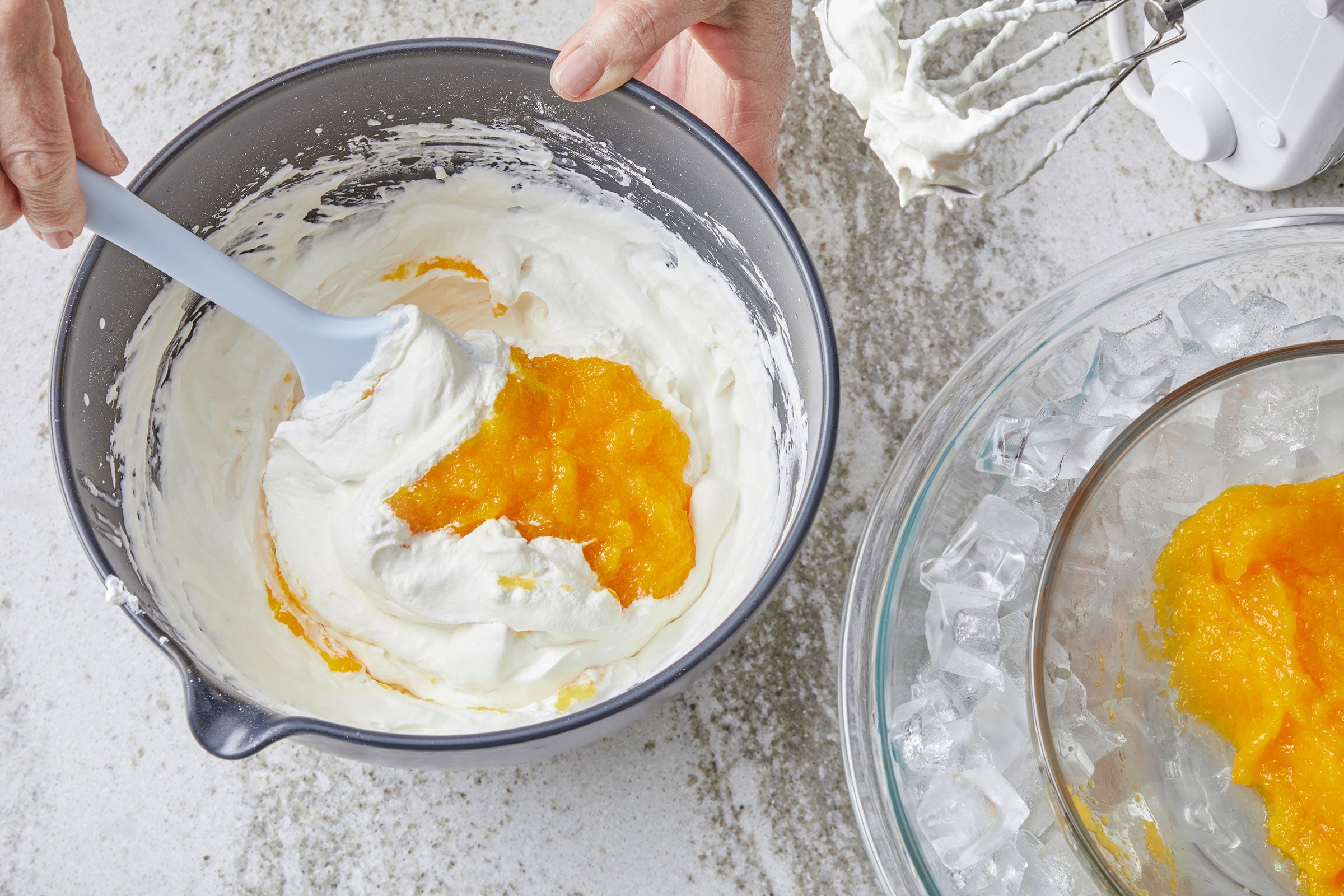 Folding the mango puree into the whipped cream in a large bowl