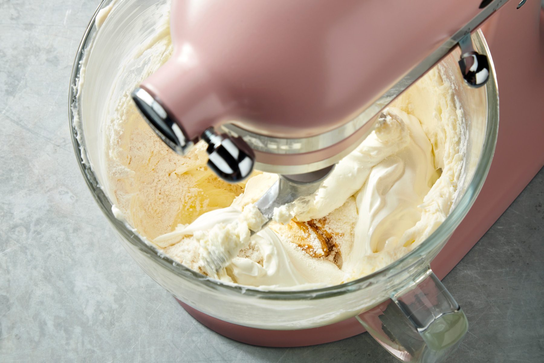 Close shot of beat in the sour cream; flour; vanilla and salt; add eggs; on a grey surface;