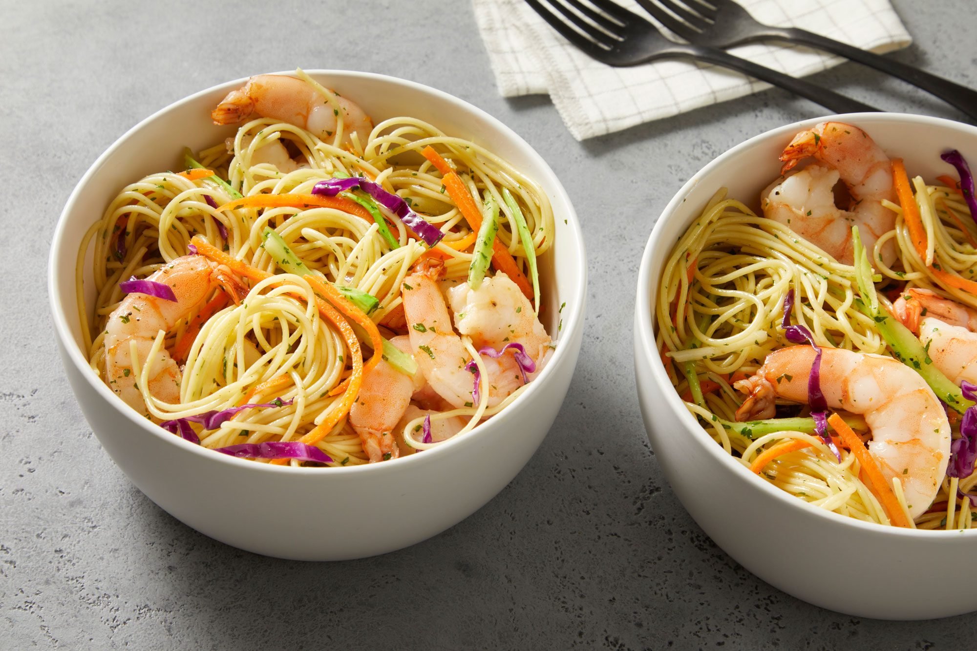 Close shot of Shrimp and Noodle Bowls; served in two bowls; with forks anf napkin; on marble surface