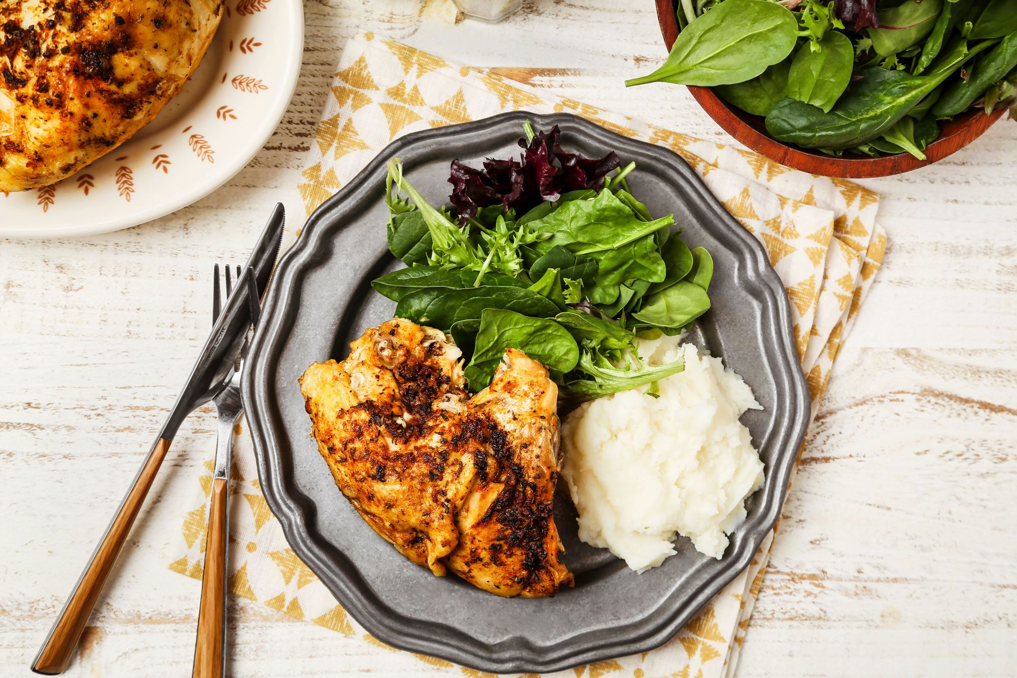 Cover push pull image of Taste of Home's Slow-Cooker Bone-In Chicken Breast shot on a white wooden surface; Bone-in chicken breasts cookedi n a slow-cooker and served on a metal plate with mashed potatoes and greens