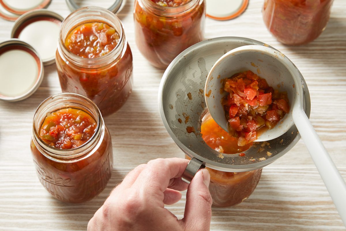 relish being ladled into sterilised pint jars