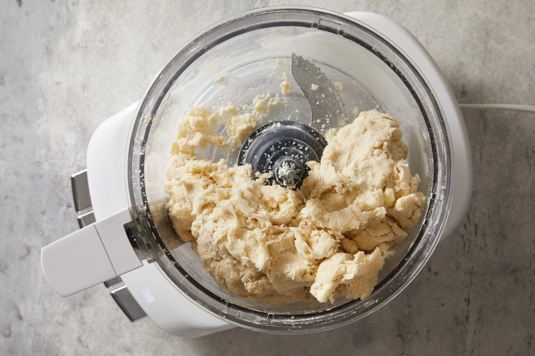 Overhead shot of add sugar and salt; pulse to combine; while pulsing gradually add ice water; 1 tablespoon at a time; until dough holds together when pressed; marble surface;