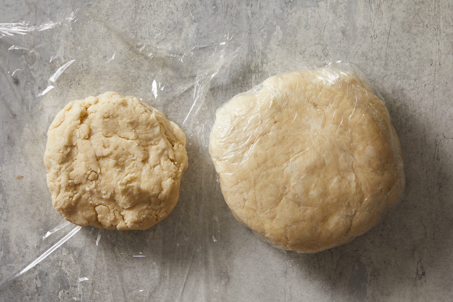 Overhead shot of divide dough into two-thirds- and one-third-sized pieces; Shape each into a disk; wrap and refrigerate 1 hour or overnight; marble surface;
