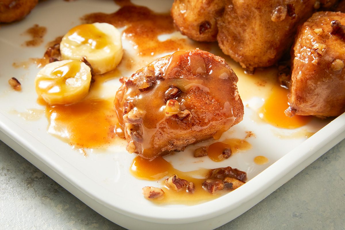 Close-up shot of Upside-Down Banana Monkey Bread; Top with sliced banana; drizzle with reserved glaze